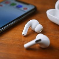 Photo of airpods on table with cellphone and case.